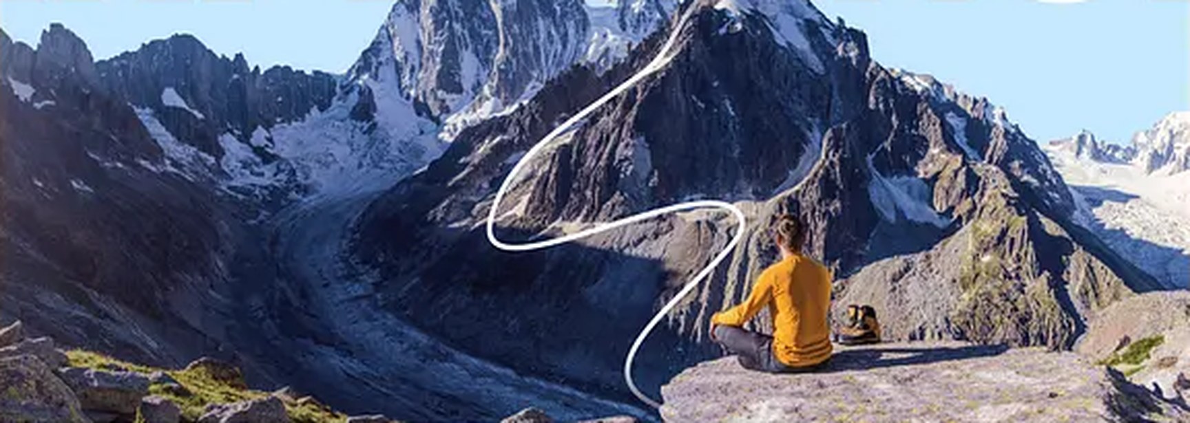 Hiker resting on a ridge facing a snowy mountain peak